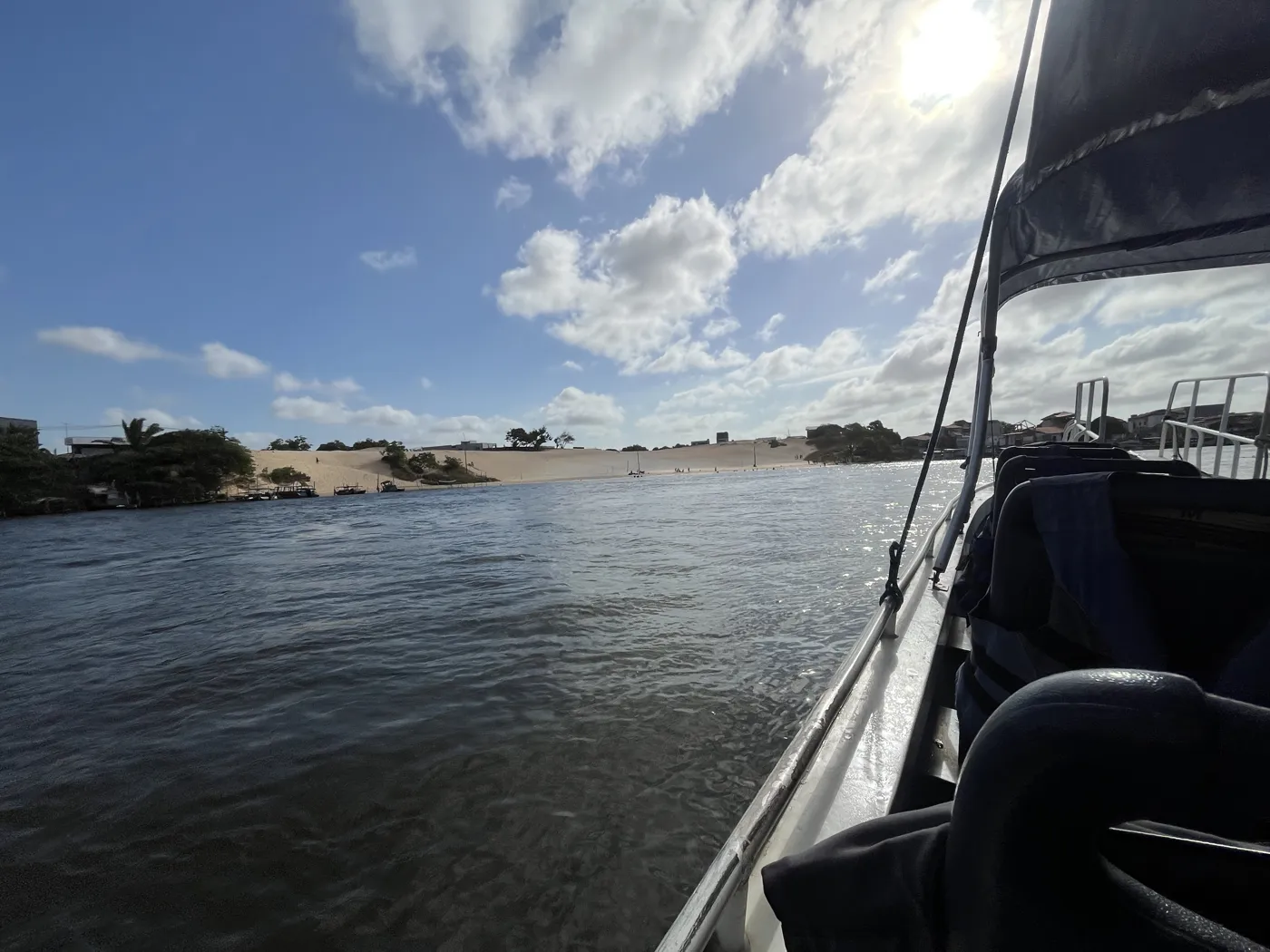 Vista desde dentro de la lancha navegando por el río Preguiças, con dunas y la orilla al fondo