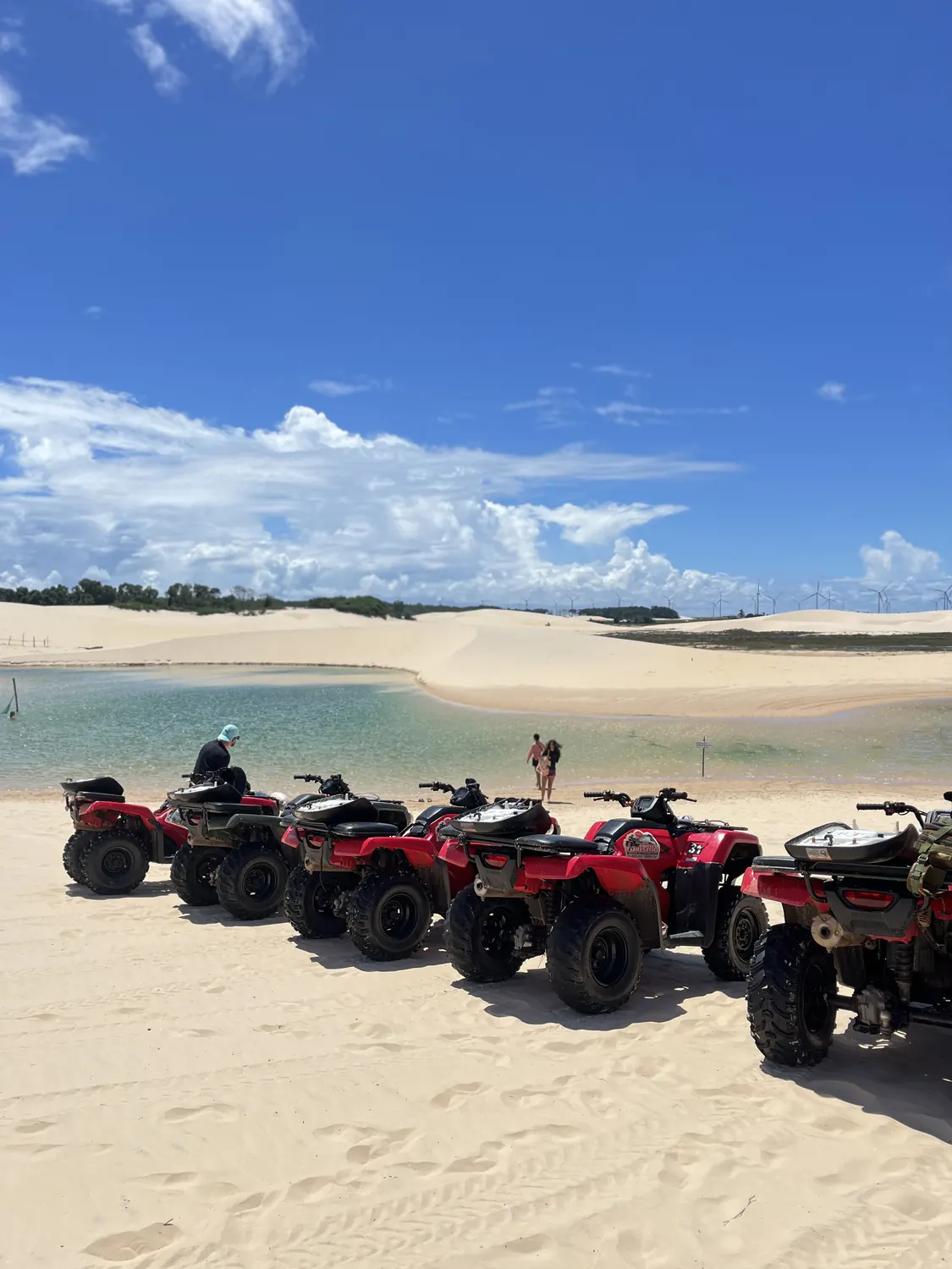 ATVs parked at the edge of a lagoon in the Pequenos Lençóis, with the dunes in the background
