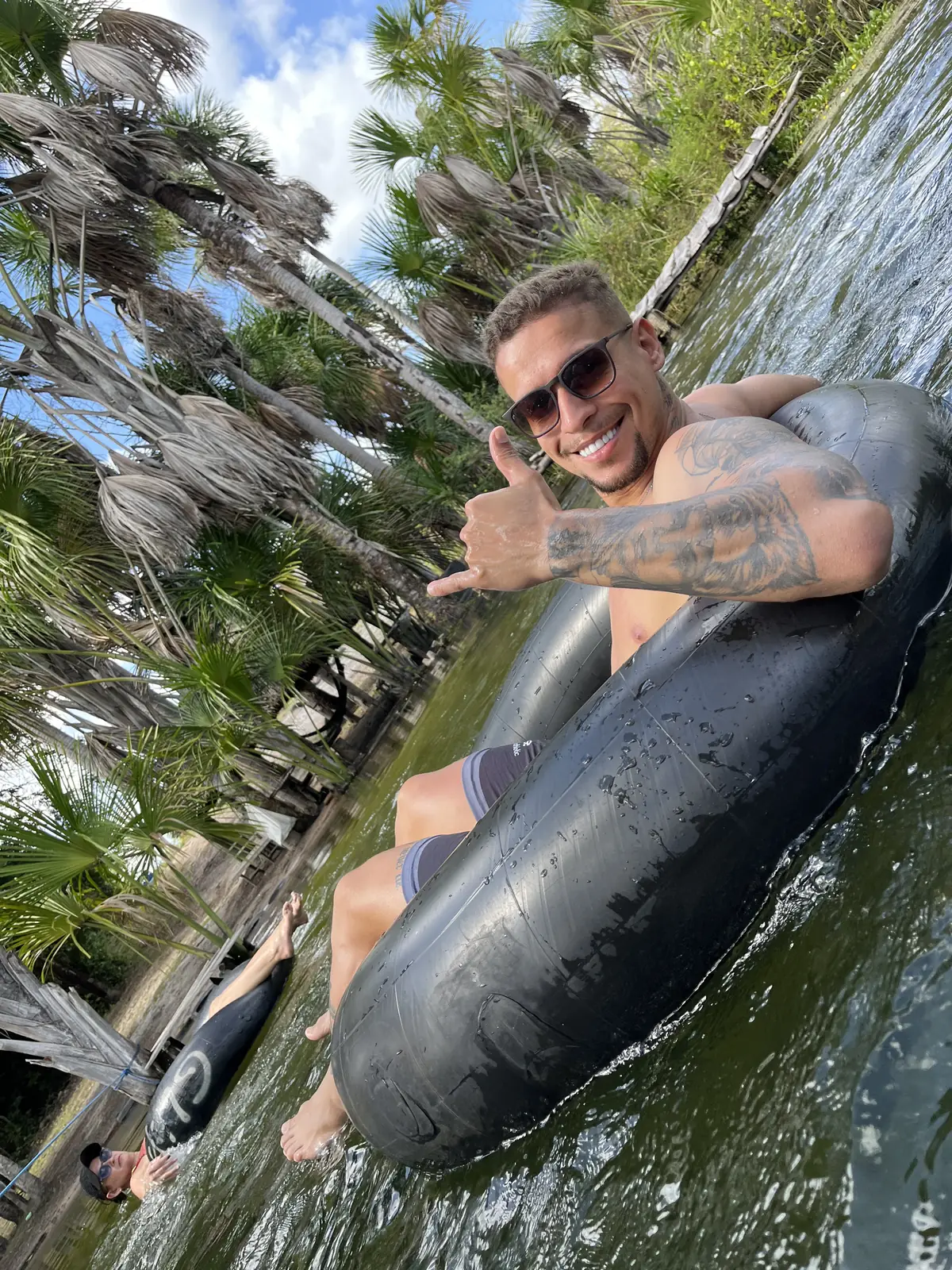 Visitante boiando pelo Rio Formiga na boia, cercado pelas palmeiras