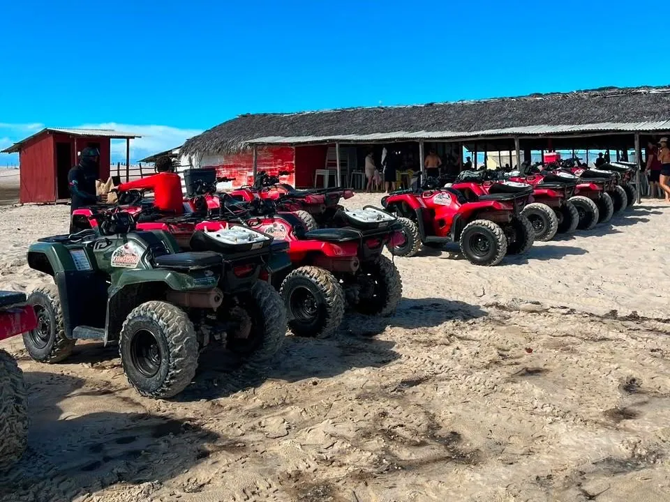 Row of ATVs parked on the sand in front of a thatched restaurant, ready to set off on the tour