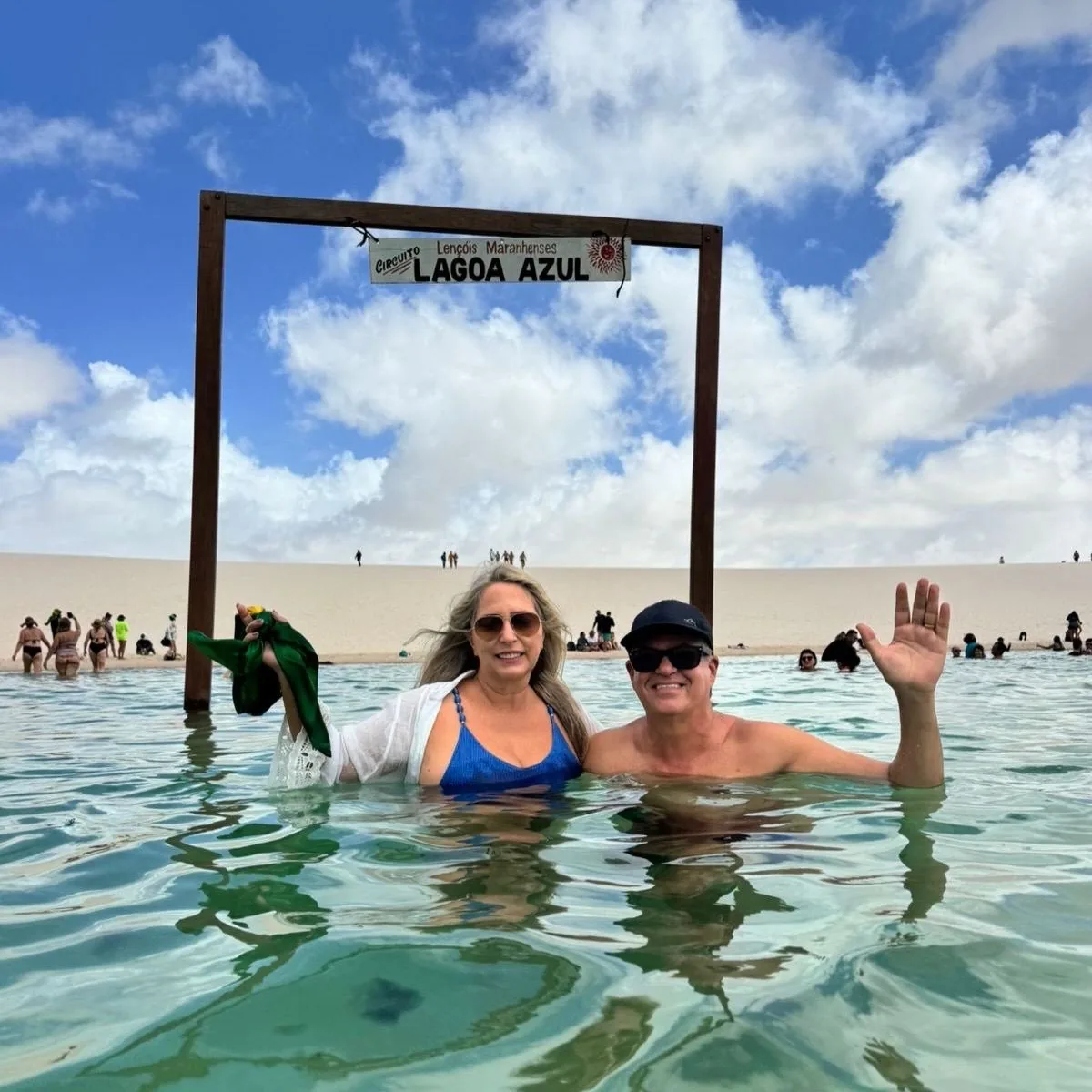 Casal no letreiro da Lagoa Azul, com águas cristalinas ao redor