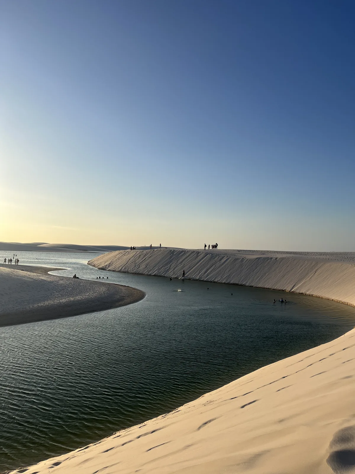 Lagoa Bonita ao fim da tarde, com visitantes no alto da duna e outros na água