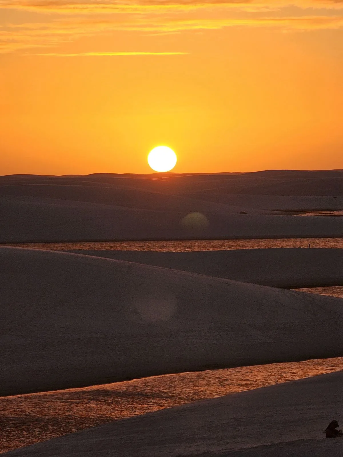 Pôr do sol visto do alto da duna, com as lagoas dos Lençóis Maranhenses ao fundo