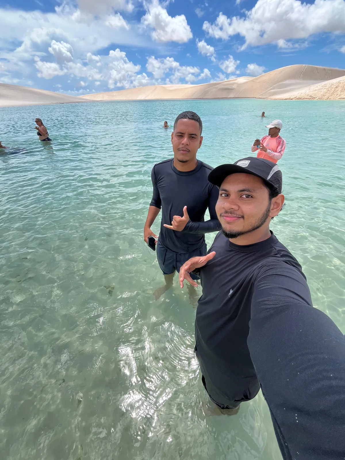 Guias da Amo Lençóis na água da Lagoa Azul, com banhistas e as dunas ao fundo