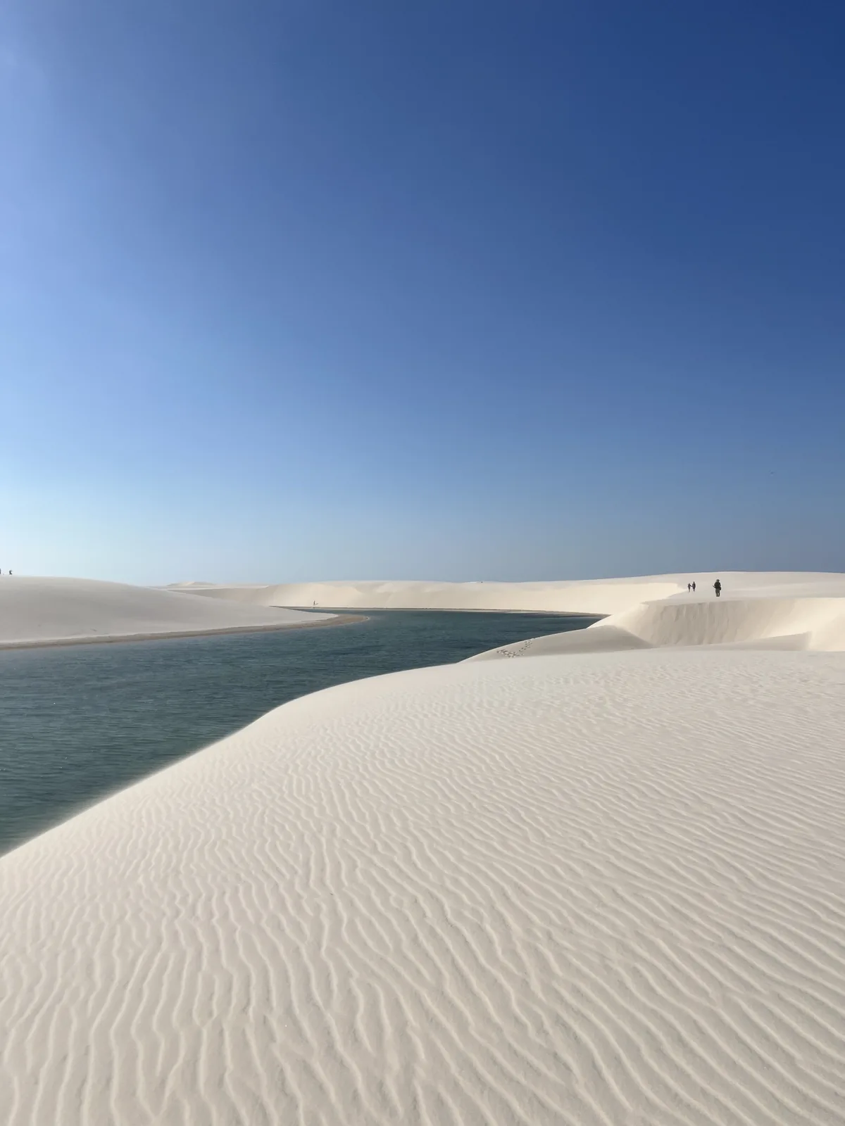 Lagoa Bonita among the white dunes, with wind-rippled sand in the foreground