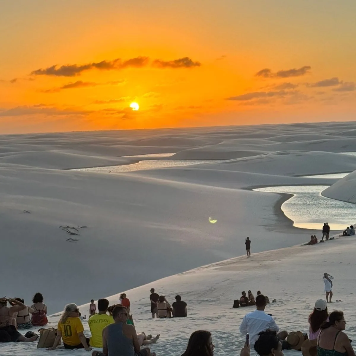 Visitors sitting on top of the Lagoa Bonita dune watching the sunset over the Lençóis
