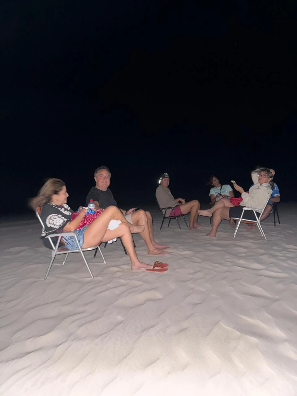 Grupo sentado nas cadeiras na areia, observando o céu noturno dos Lençóis