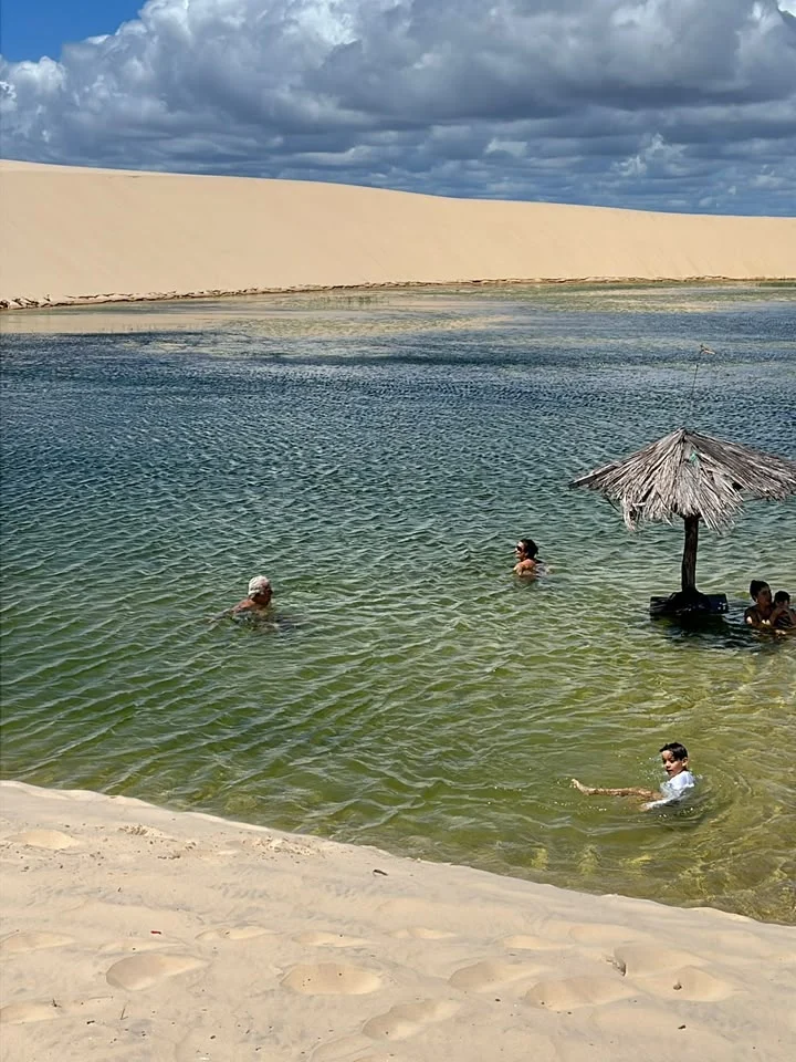Visitantes tomando banho em uma lagoa entre as dunas, parada do passeio de quadriciclo
