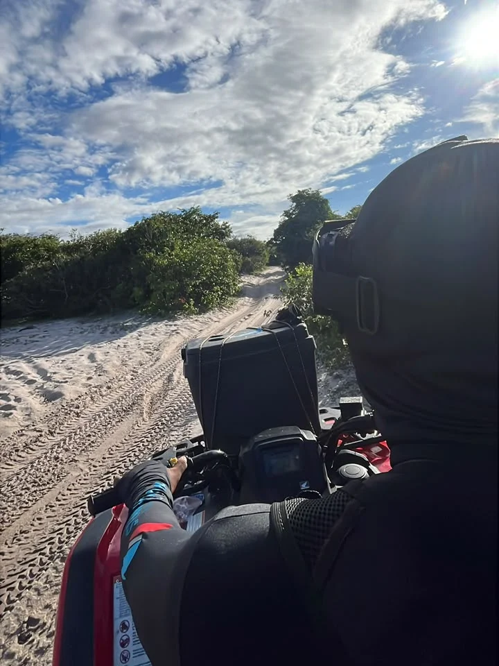 Vista de cima do quadriciclo seguindo por uma trilha de areia entre a vegetação