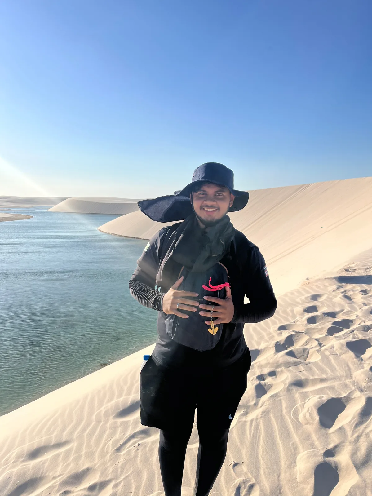 Brian Dutra, da Amo Lençóis Turismo, no alto de uma duna ao lado de uma lagoa nos Lençóis Maranhenses