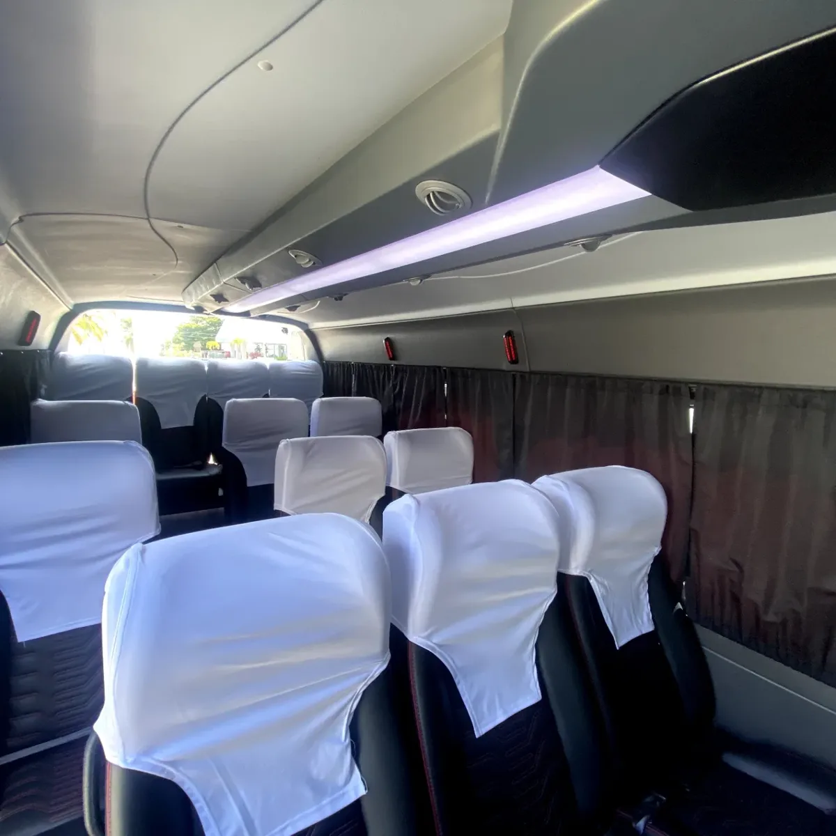 Interior of the transfer van, with reclining seats with white covers, curtains and air conditioning