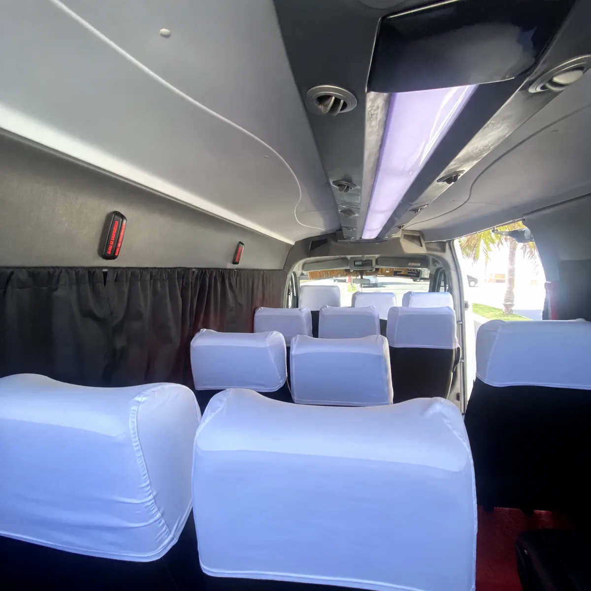 Interior of the transfer van seen from the back, with the rows of seats and the aisle