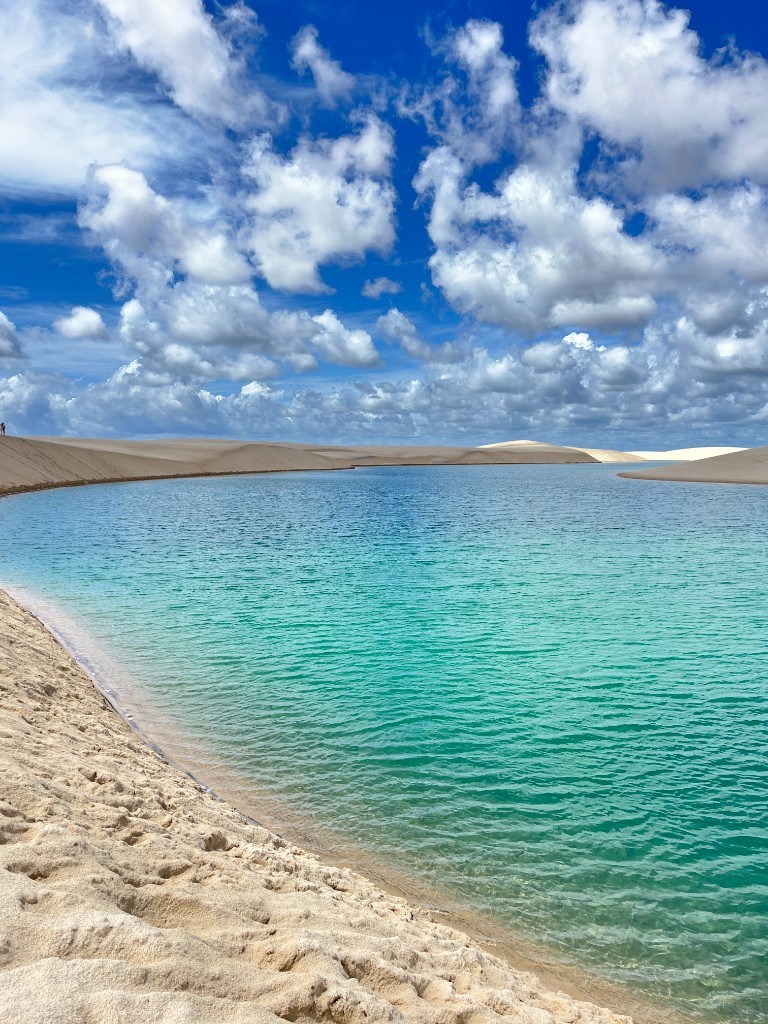 Lagoa cristalina e dunas sob céu azul