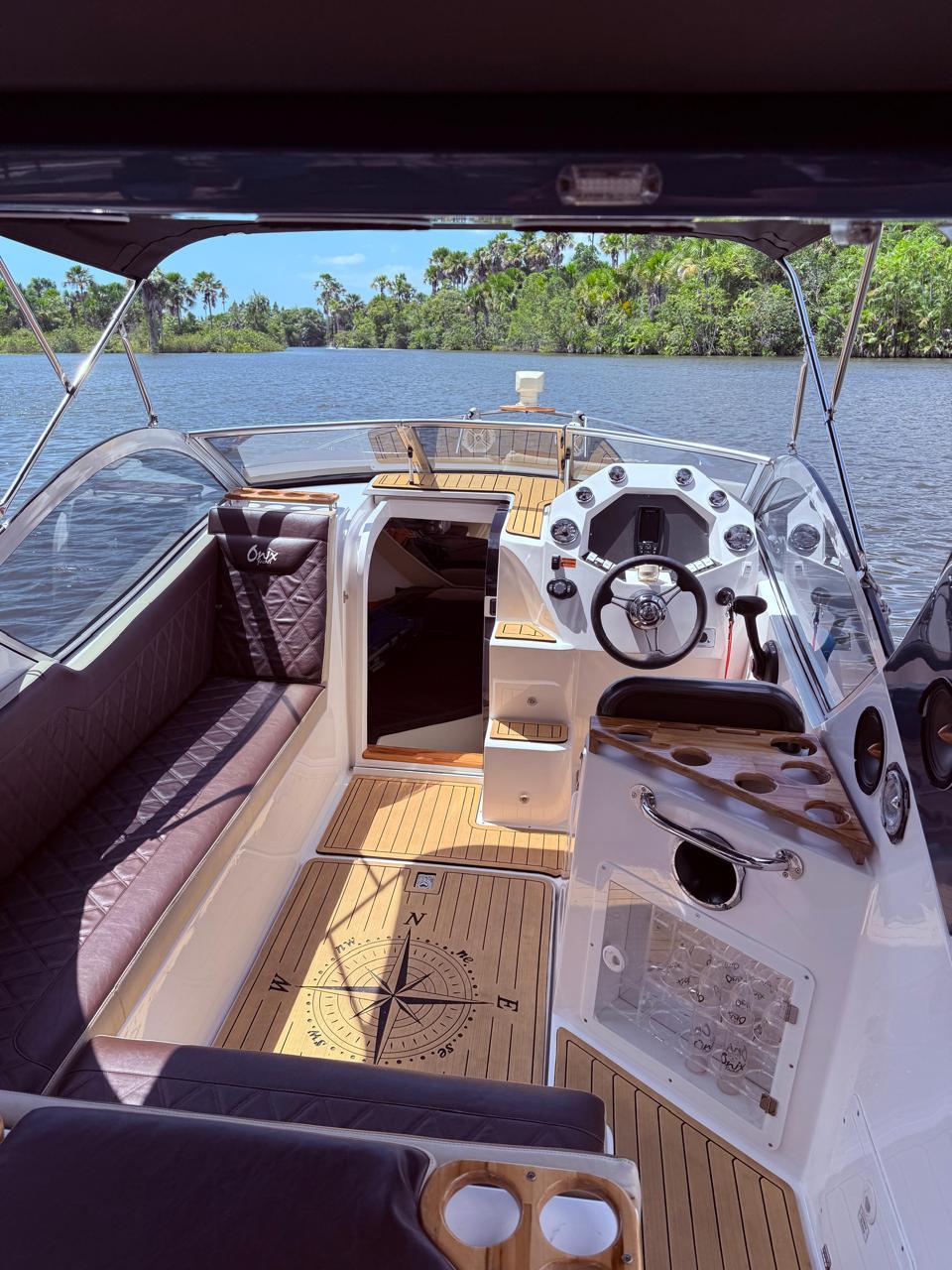 Interior amplo da lancha de luxo com timão, deck em madeira e rosa dos ventos