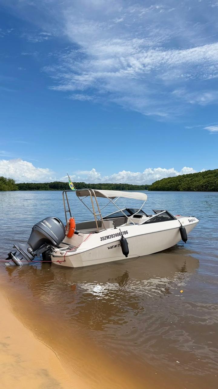 Lancha Zagaia atracada na praia com céu azul ao fundo